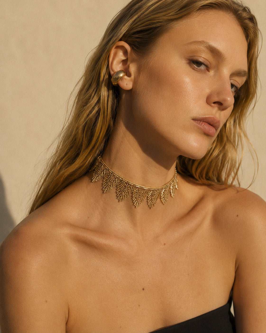 Modelo llevando TELMA CHOKER dorado con pedrería de fantasía y diseño de flecos